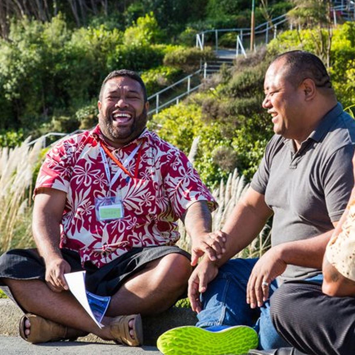 Two Pasifika men sitting talking and laughing