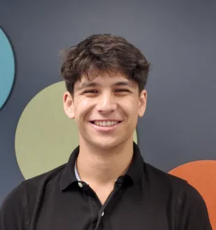 Harrison Hawkins smiling headshot. He has short brown hair and wears a black polo shirt