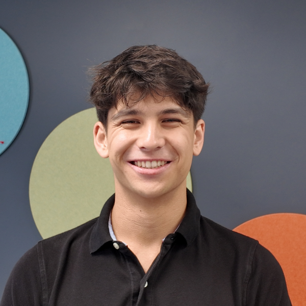 Harrison Hawkins smiling headshot. He has short brown hair and wears a black polo shirt