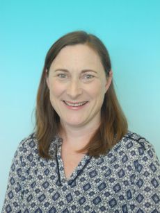 Smiling headshot of Tish Kirkland. She has shoulder length brown hair and wears a blue patterned top