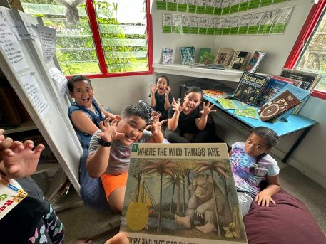 A group photo of children at the library imitating being characters from ‘Where the Wild Things Are.’