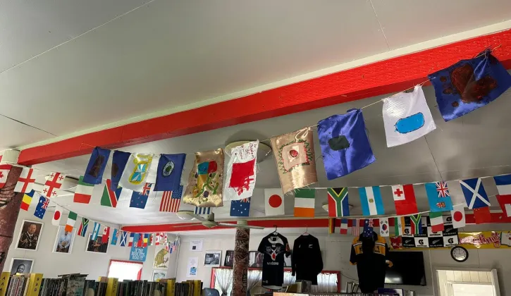 Photo of the Kolovai library shelves filled with books. Above them are a collection of different country flags and hand made ones for the kingdoms.