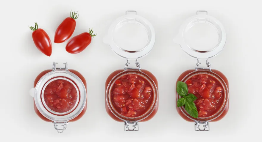 Birds eye view of three jars of pasta. The first is closed with tomatos above it. The socnd jar is open showing the sauce inside. The third is also open and the sauce is topped with basil leaves.