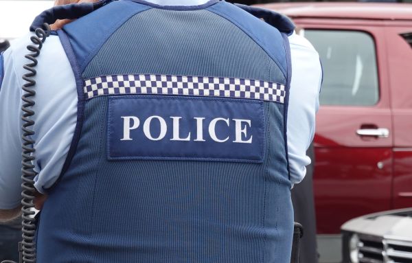 A close up of a unifromed police officers vest with the word 'Police'