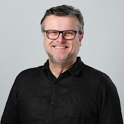 Smiling headshot of Steve Adams. He wears dark framed glasses and a black shirt.