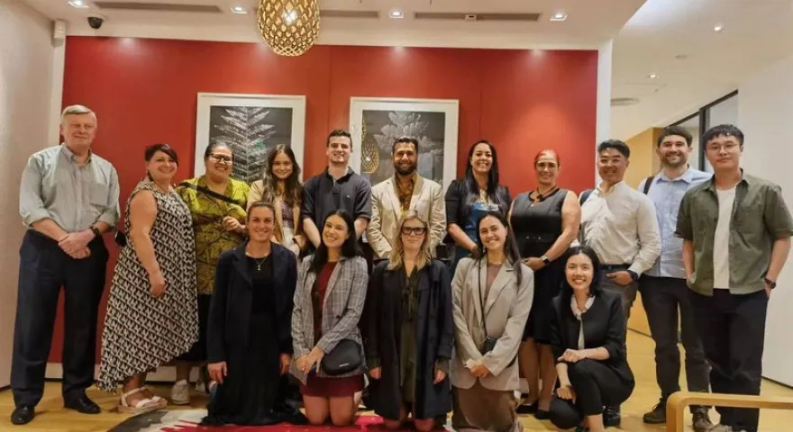 A group of people standing and sitting in front of a red wall with art on it at the NZTE office in Guangzhou.