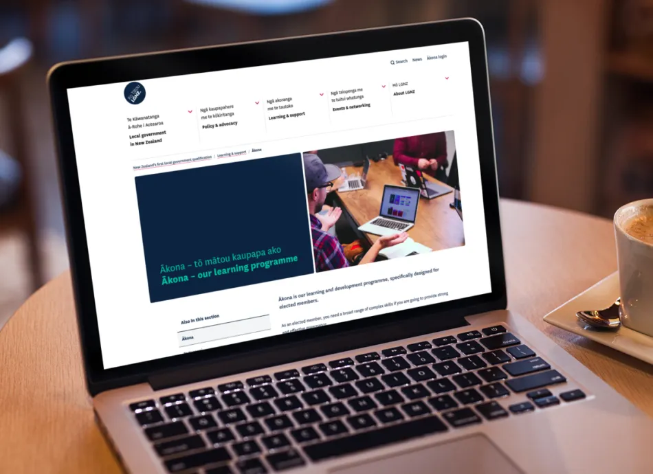 Open laptop displays the LGNZ website showing the landing page for Ākona, the digital learning platform for elected members. Next to the laptop is a flat white.