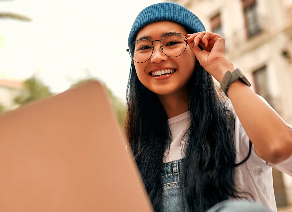 Female student wearing glasses and a blue beanie hat smiling
