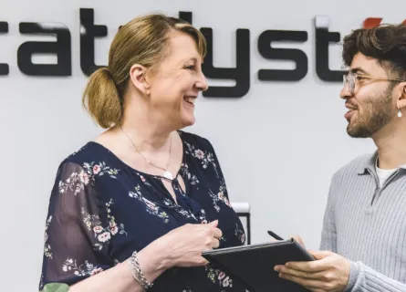 Two people smiling while talking about the content on a tablet device