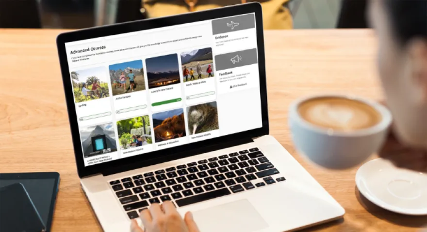 The advanced courses for travel sellers on Tōtara are open on a laptop where a man drinks his coffee as he looks at his screen