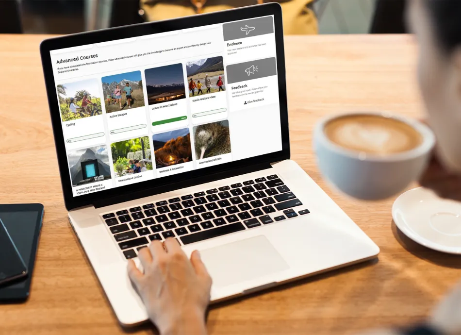 The advanced courses for travel sellers on Tōtara are open on a laptop where a man drinks his coffee as he looks at his screen