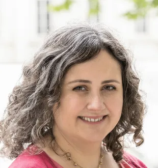 Smiling headshot of Cathy Elliott. She has brown curly hair and wears a pink shirt.