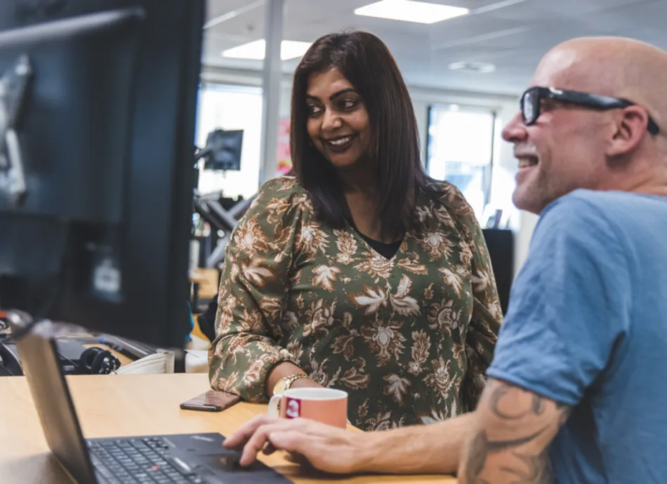 A man and woman smiling looking at a computer screen