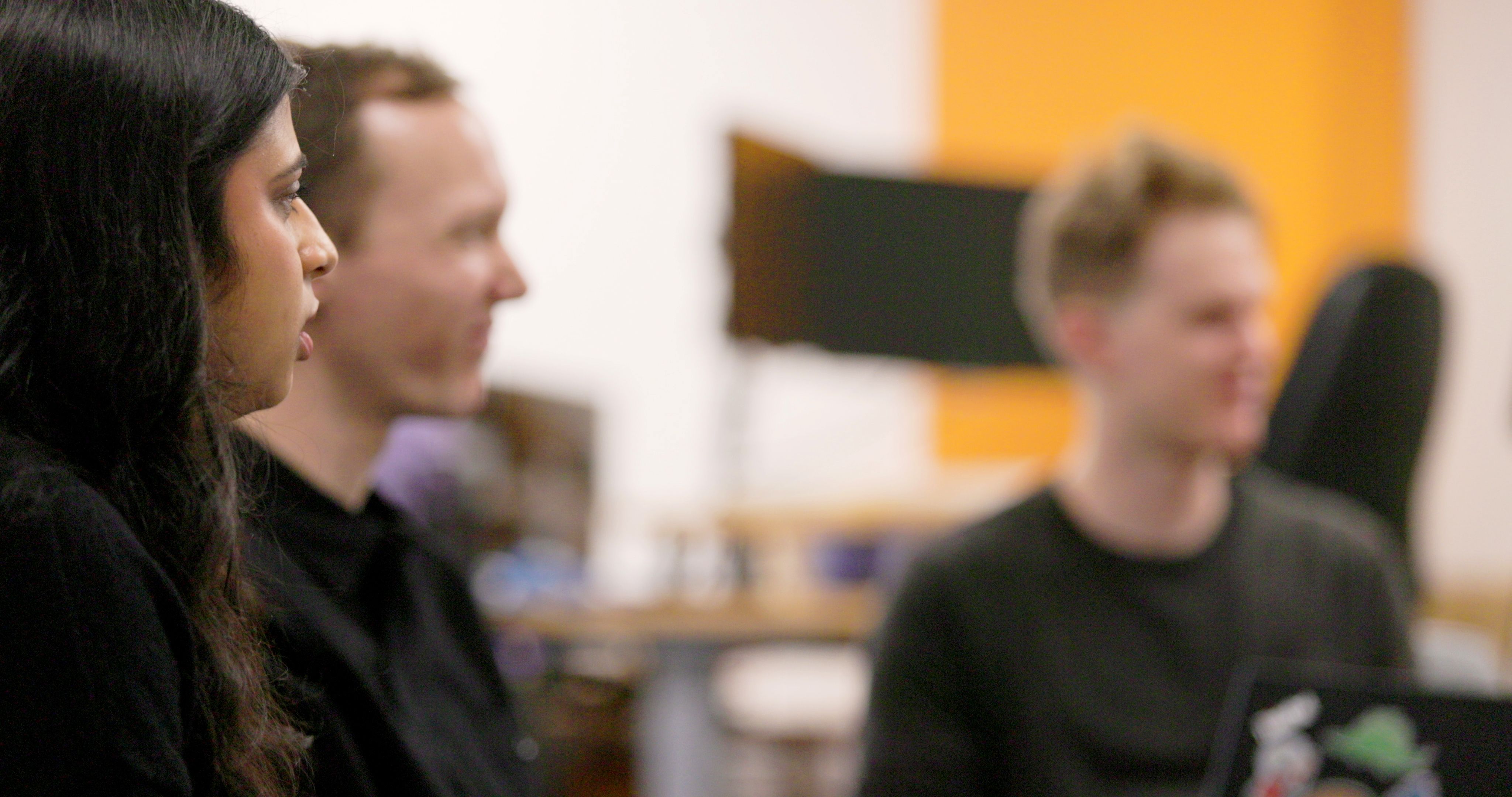 A close oup of two men with a unfocused computer screen in the background