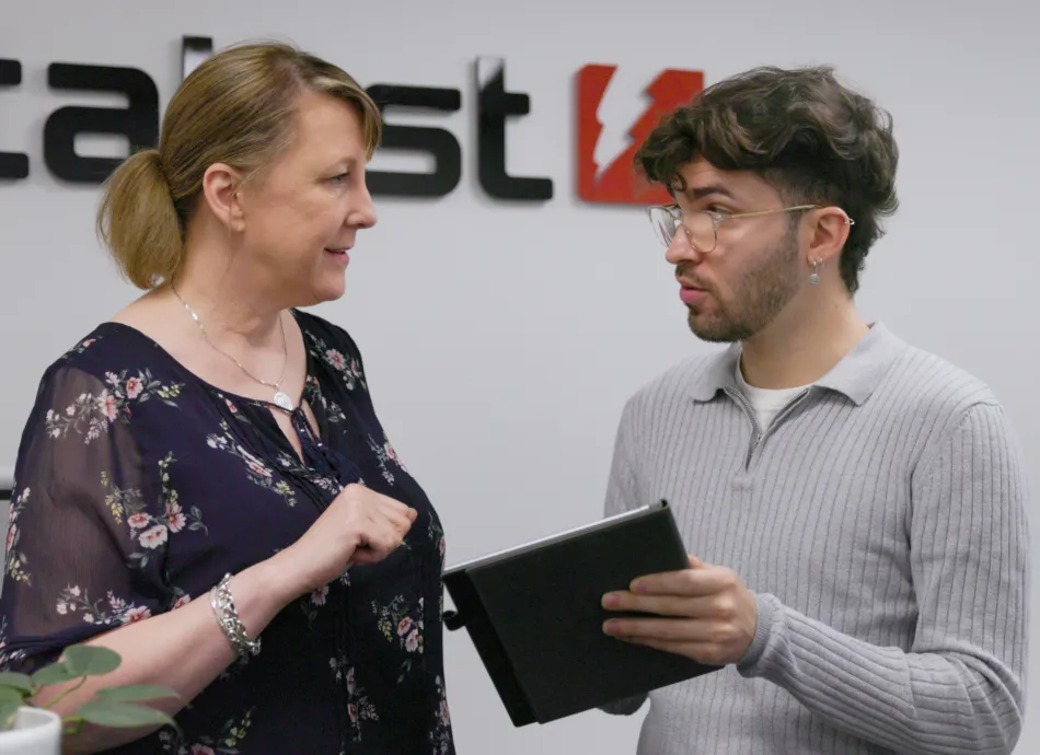 A man and woman holding an ipad and smiling at eachother