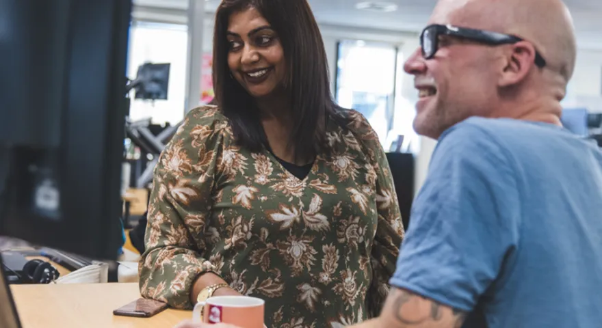 A female and male Catalyst employees huddle around a computer and smile at the screen