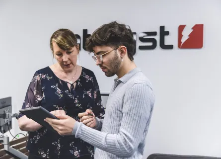 Man and woman looking at a tablet. A sign for Catalyst logo is behind them on the wall.
