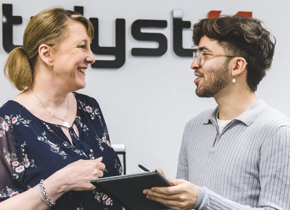 Two people smiling while talking about the content on a tablet device