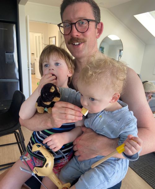 Picture of a father holding his 2 children at Christmas